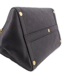 Black leather handle bag close-up of strap panel with gold rivets and monogram embossing.