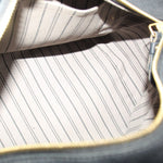 Open bag interior with light striped lining and gold zipper edge visible.