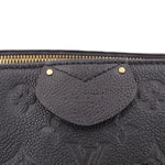 Black monogram bag close-up with curved front pouch, gold snap details, and zipper top.