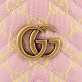 Close-up of gold-toned GG logo emblem on pink GG monogram crossbody fabric.