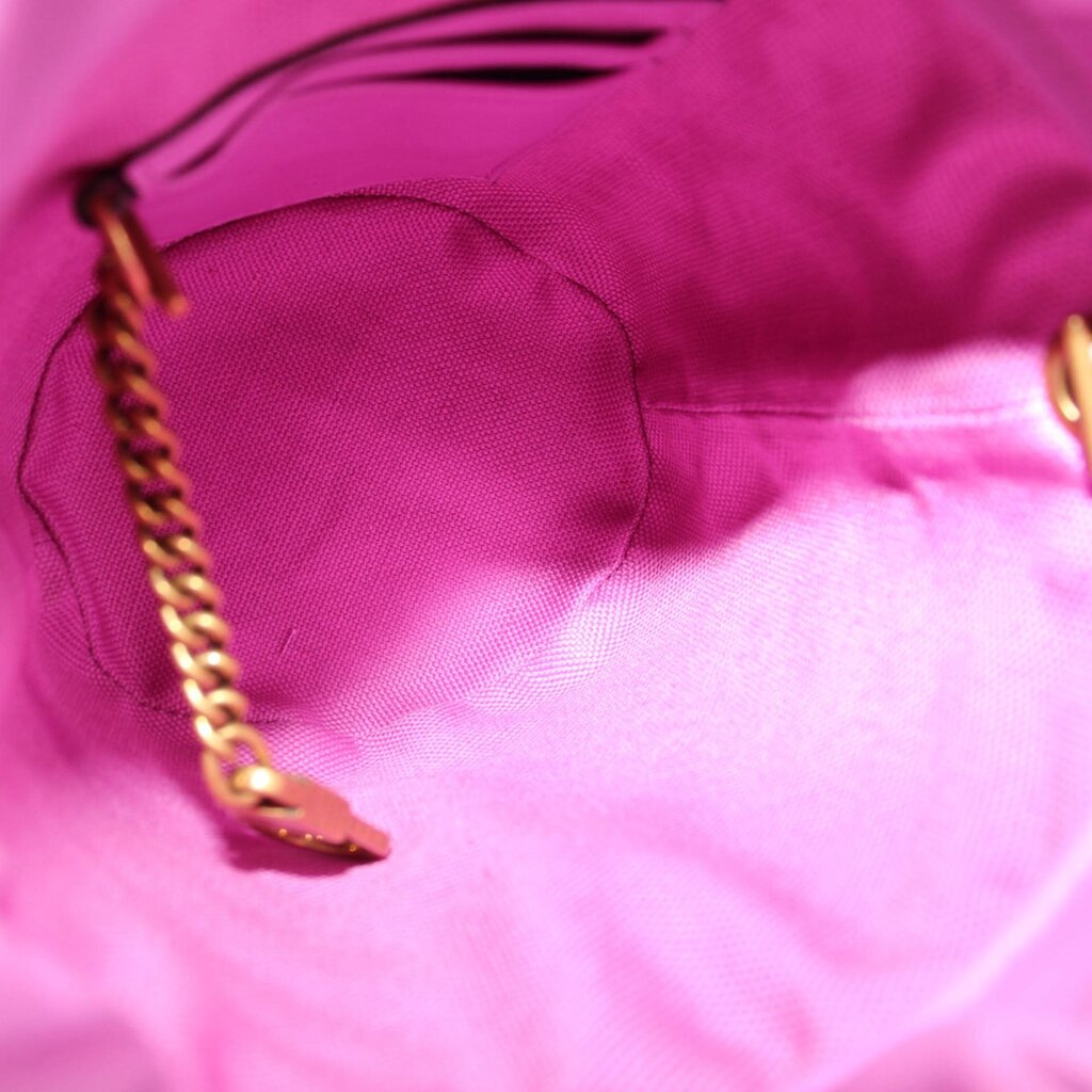 Close-up of pink fabric bucket opening edge with gold-toned chain detail inside.