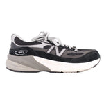 New Balance sneaker side view with black suede, gray mesh panels, and a thick cushioned sole