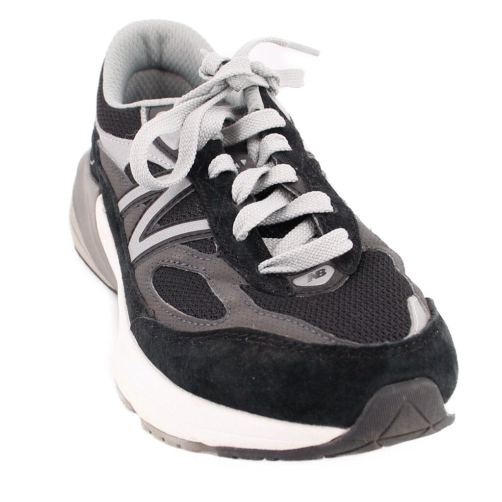 New Balance black and gray suede sneakers with mesh panels, white laces, and cushioned soles