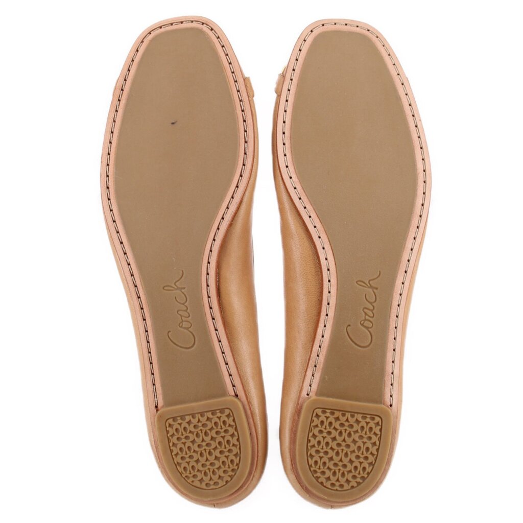 Tan leather flat soles with Coach logo and textured traction pads.