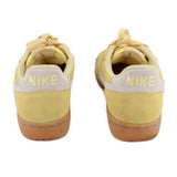 Yellow suede Nike sneakers with 'NIKE' heel text and cream laces