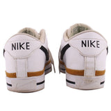Pair of white Nike leather sneakers showing branded heels and tan midsole stripes