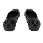 Black patent ballet flats with rear seam and embossed logo medallion at toe