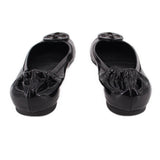 Black patent ballet flats with rear seam and embossed logo medallion at toe