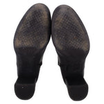 Black leather ankle boot pair outsole view with dark rubber heel tread.