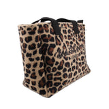 Leopard-print tote shown from the side, with black handles and a wide base