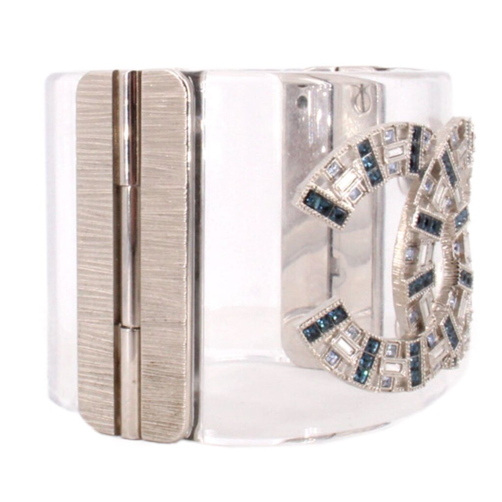 CHANEL clear cuff bracelet shown from the side, with a metal hinge and jeweled logo