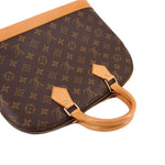 Monogram bag front with tan leather straps and two gold-tone zipper tabs