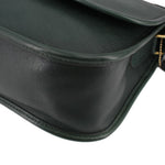 Close-up of the dark green leather bag's side seam and rounded corner