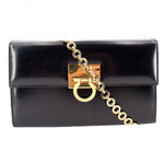 Black leather crossbody bag with gold Gancini-style clasp and chain strap