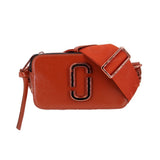 Rust leather snapshot camera bag with front J logo and top zipper, crossbody strap