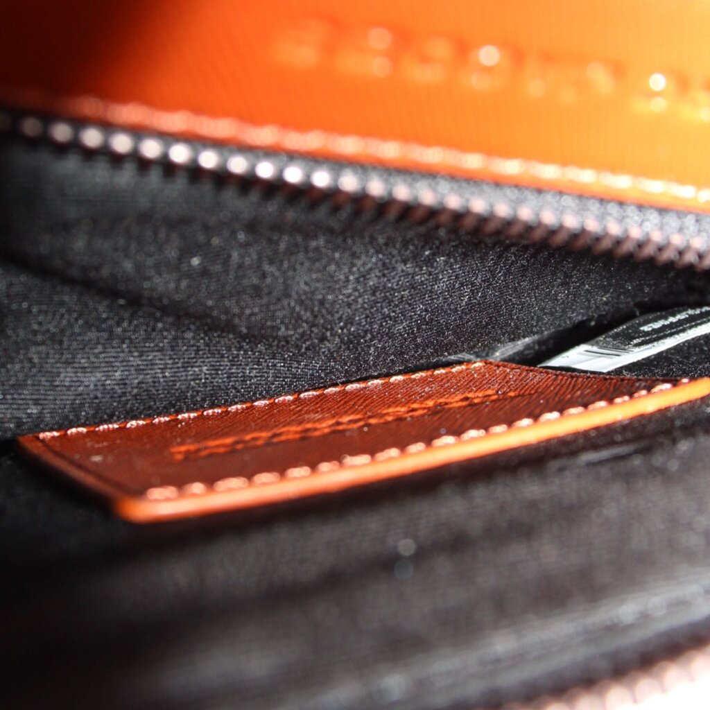 Close-up of rust leather bag zipper and interior lining with stitch detail