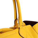 Close-up of yellow pebbled leather tote handles and stitched handle attachments