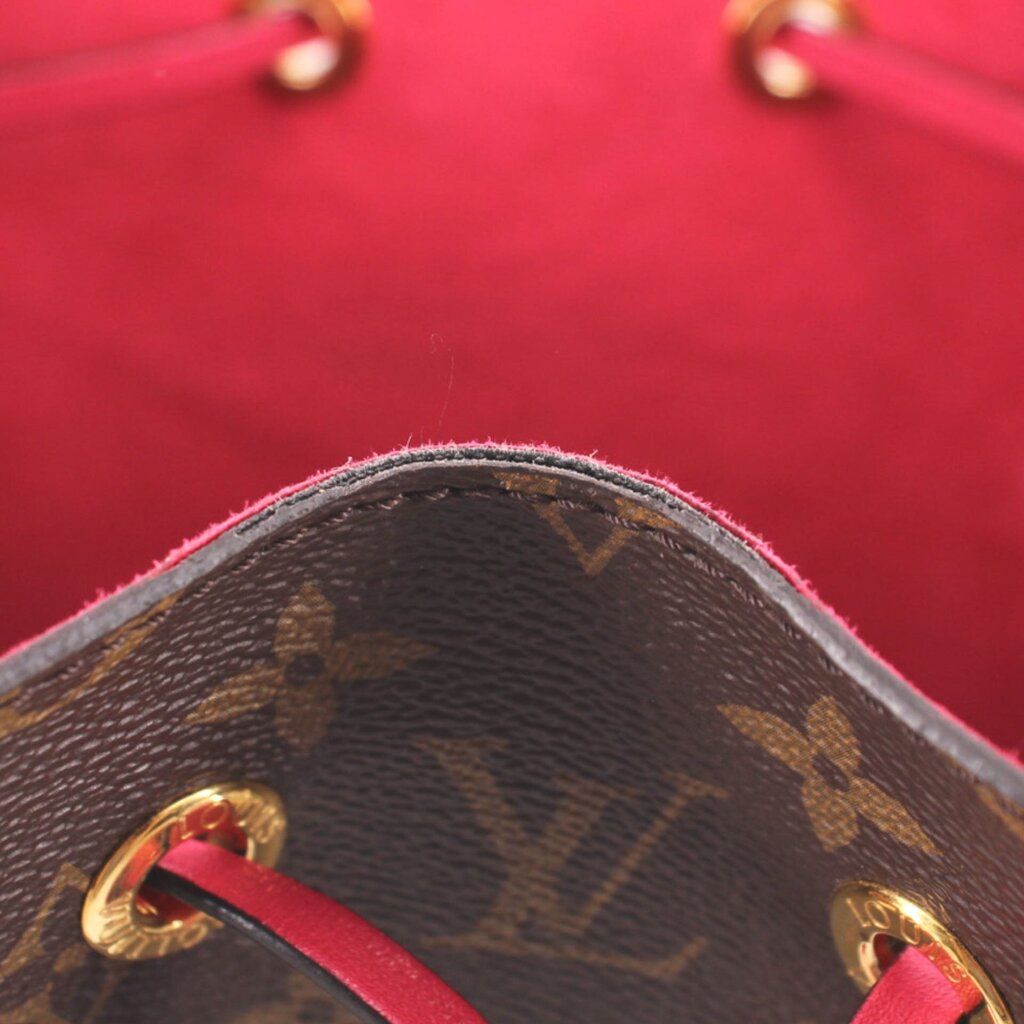 Close-up of red-lined bag interior, monogram edge and gold-tone grommets