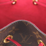 Close-up of red-lined bag interior, monogram edge and gold-tone grommets