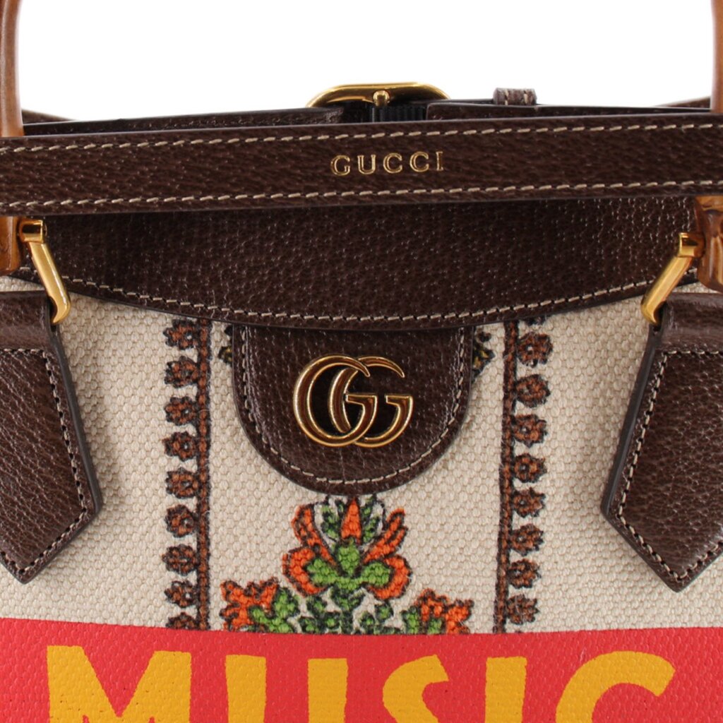 GUCCI tote close-up of gold GG clasp, brown leather trim, and floral fabric
