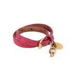 Pink leather wrap bracelet with gold-tone buckle, skull charm and round medallion