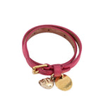 Pink leather wrap bracelet shown coiled, with gold-tone skull and round medallion charms