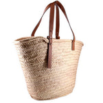 LOEWE palm-leaf tote shown from the side, with brown leather handles