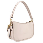 Angled view of the cream COACH Swinger bag with gold-tone hardware and hangtag