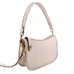 COACH Swinger cream leather bag shown at an angle with detachable crossbody strap
