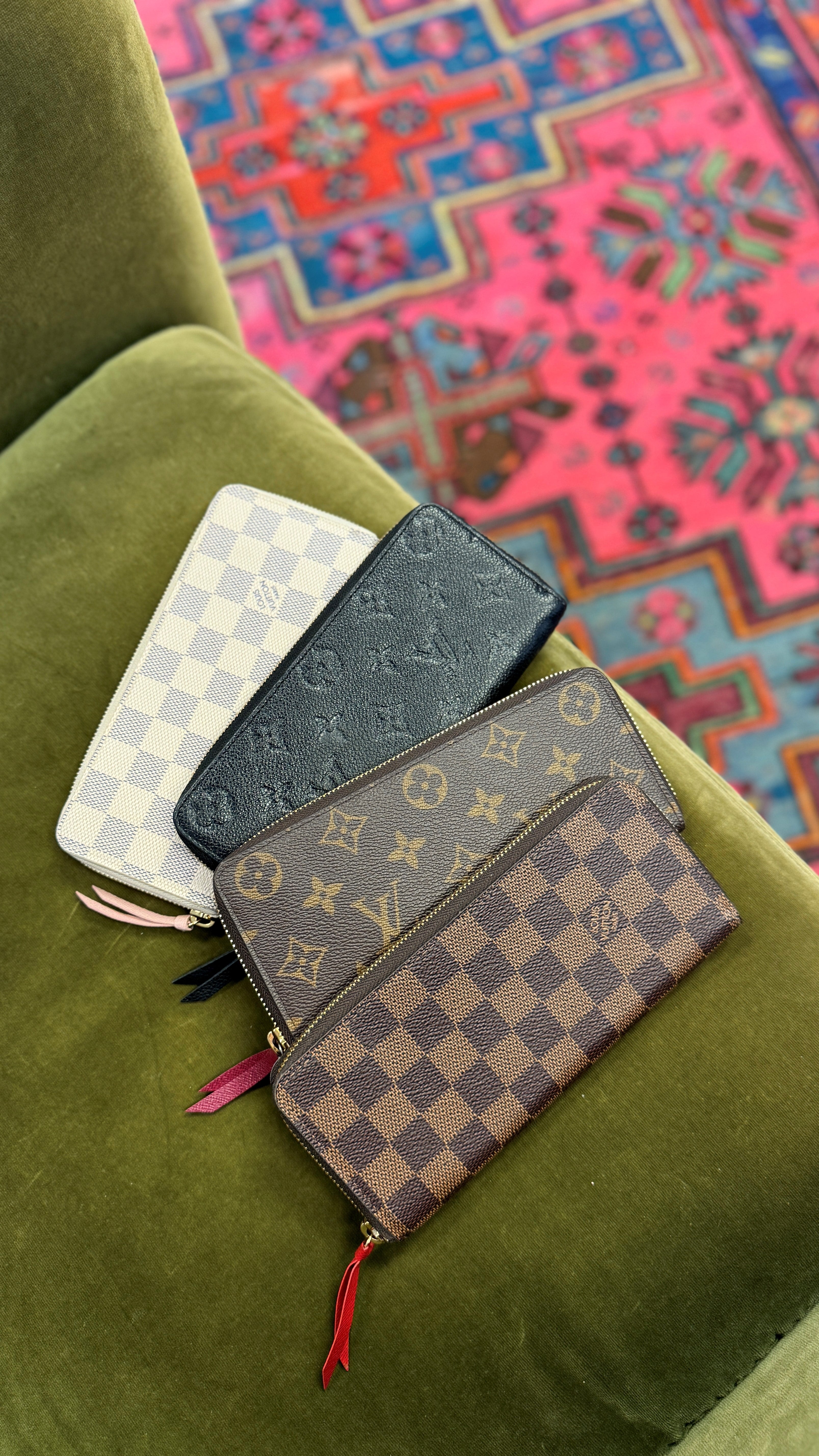 A picture of four Louis Vuitton wallets (Damier Azur, Black Empreinte, Monogram, and Damier Ebene) overlaid on top of each other on a green chair.