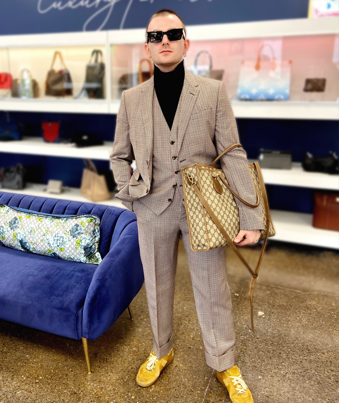 Man wearing a Gucci suit, carrying a Gucci handbag.