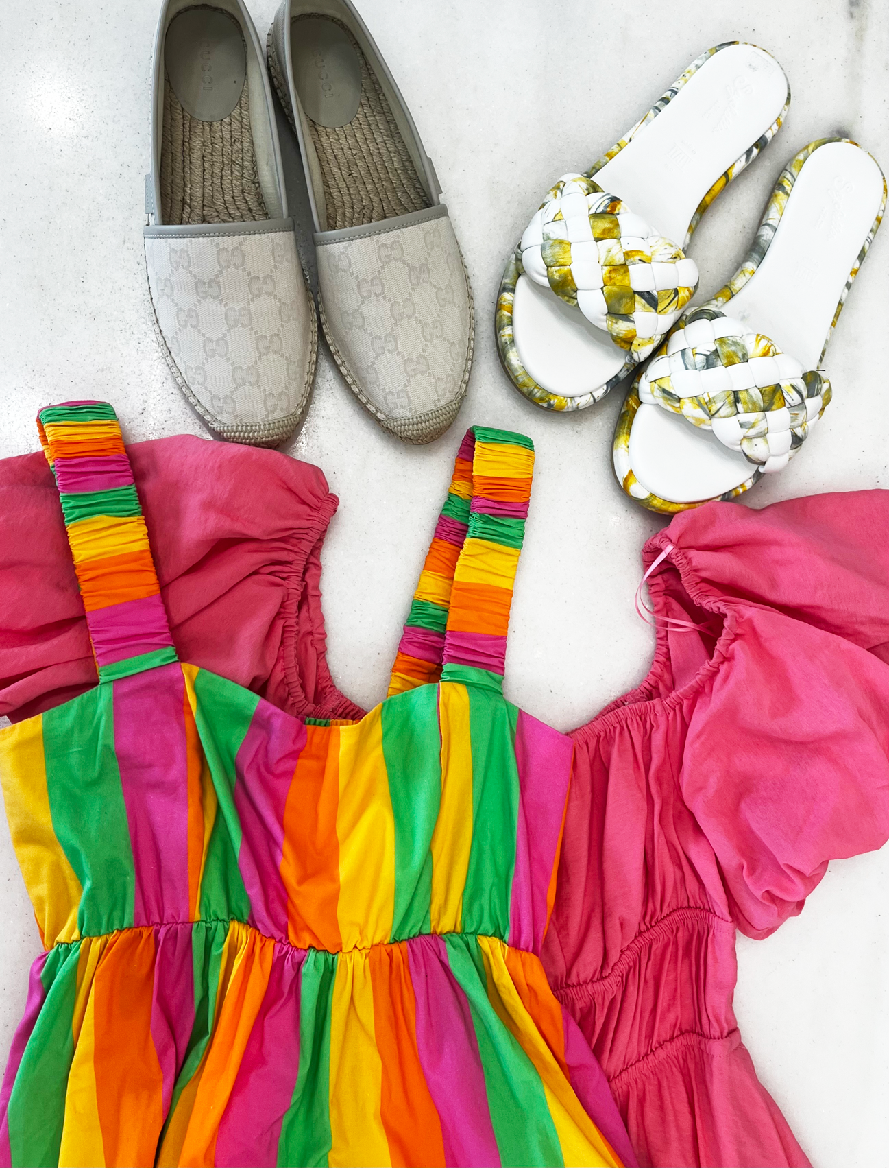 Colorful striped dress with pink top, gray loafers, and patterned sandals on a white background