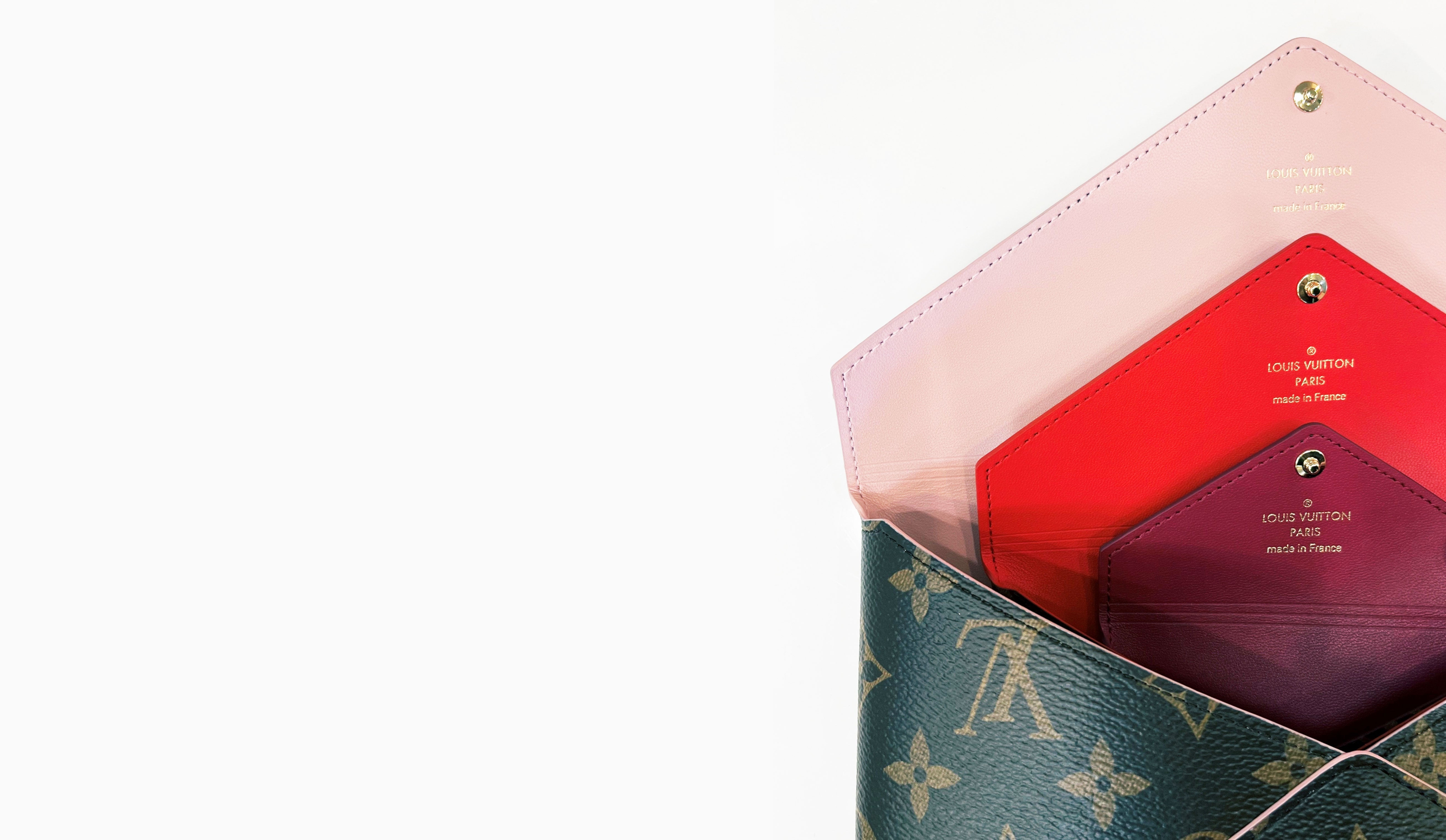 Three pink & red Louis Vuitton Envelope pouches nested inside one another.