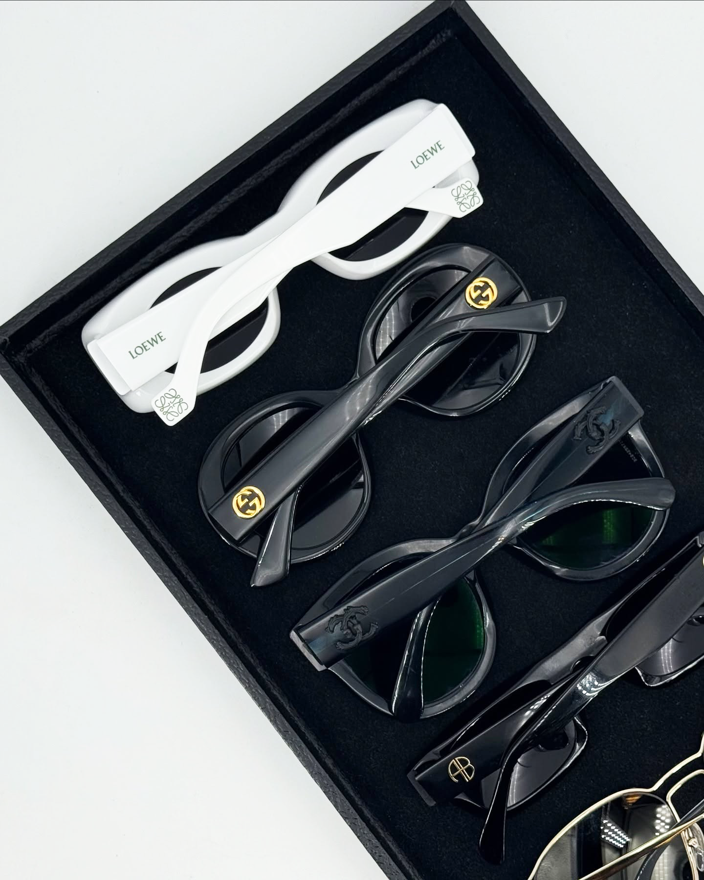 A collection of sunglasses in a black tray.
