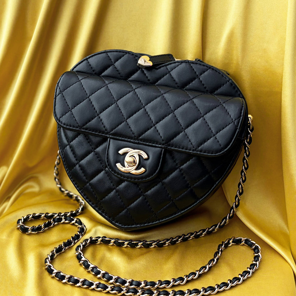 A quilted Chanel heart handbag on a yellow textile background.