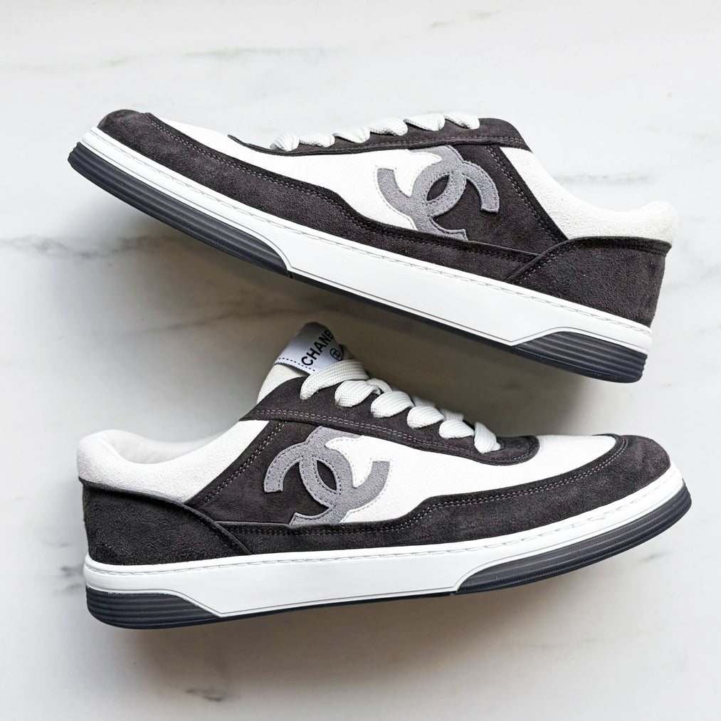 Pair of black and white sneakers with Chanel logo on a light gray background