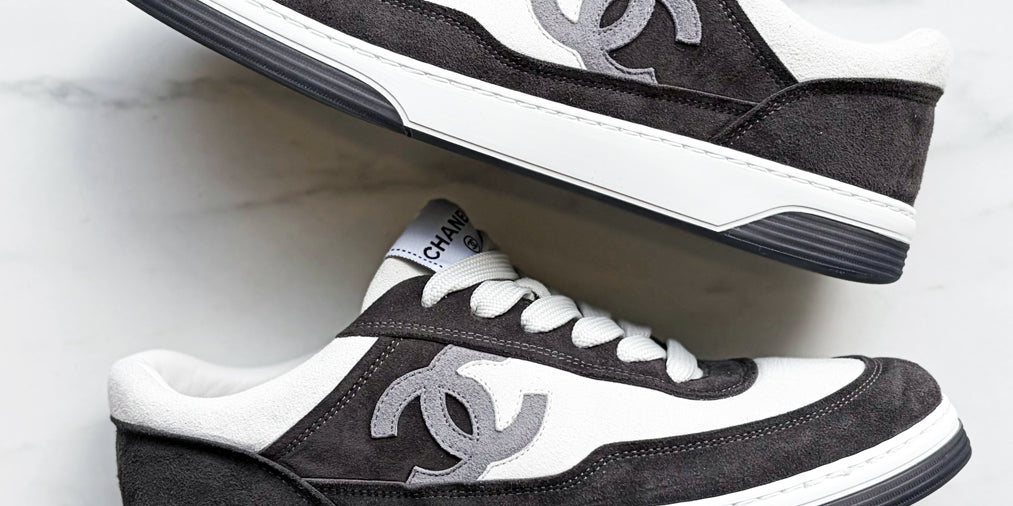 Pair of black and white sneakers with Chanel logo on a light gray background