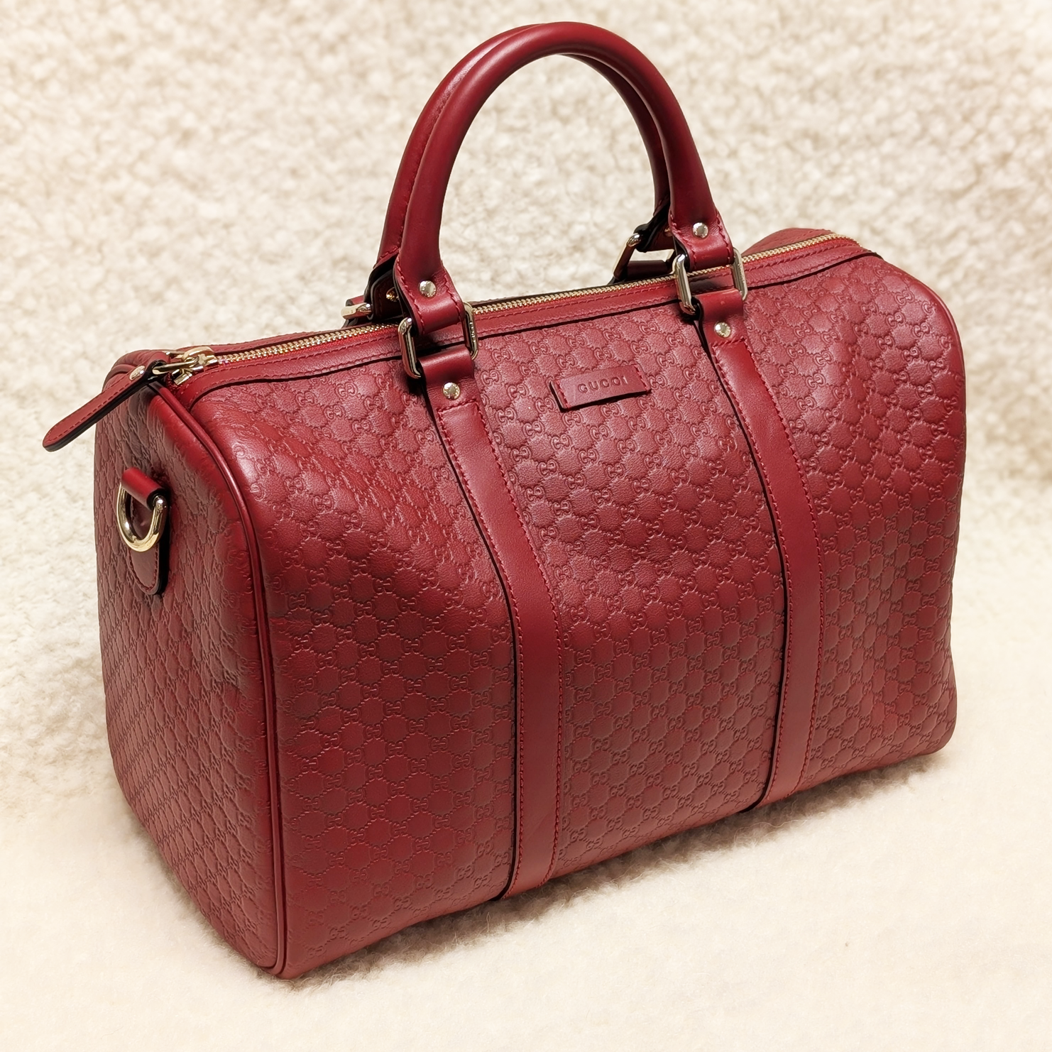 Red Gucci Boston Joy handbag on a cream shearling background.