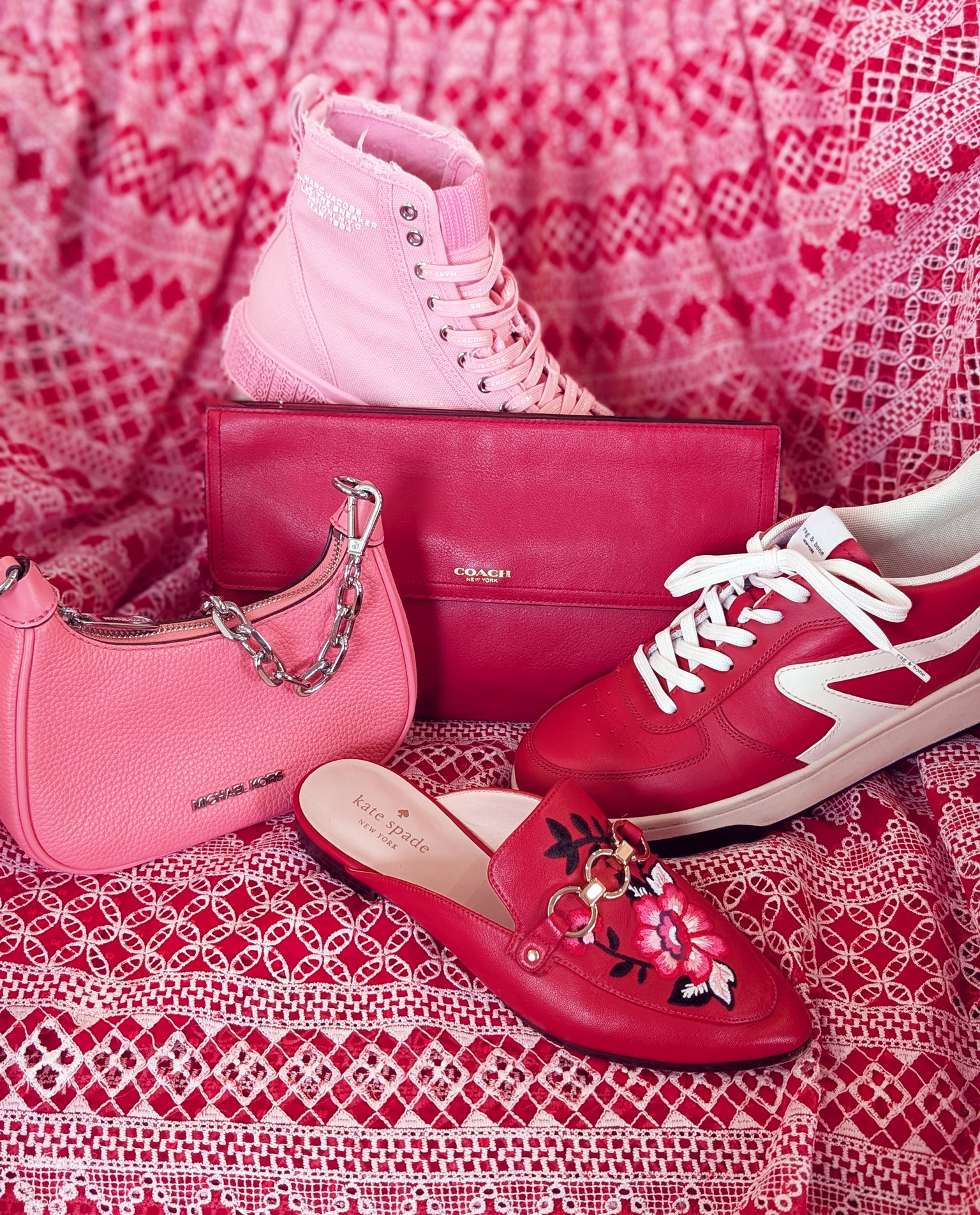 Pink handbag, red sneakers, and red loafers on a pink patterned fabric background