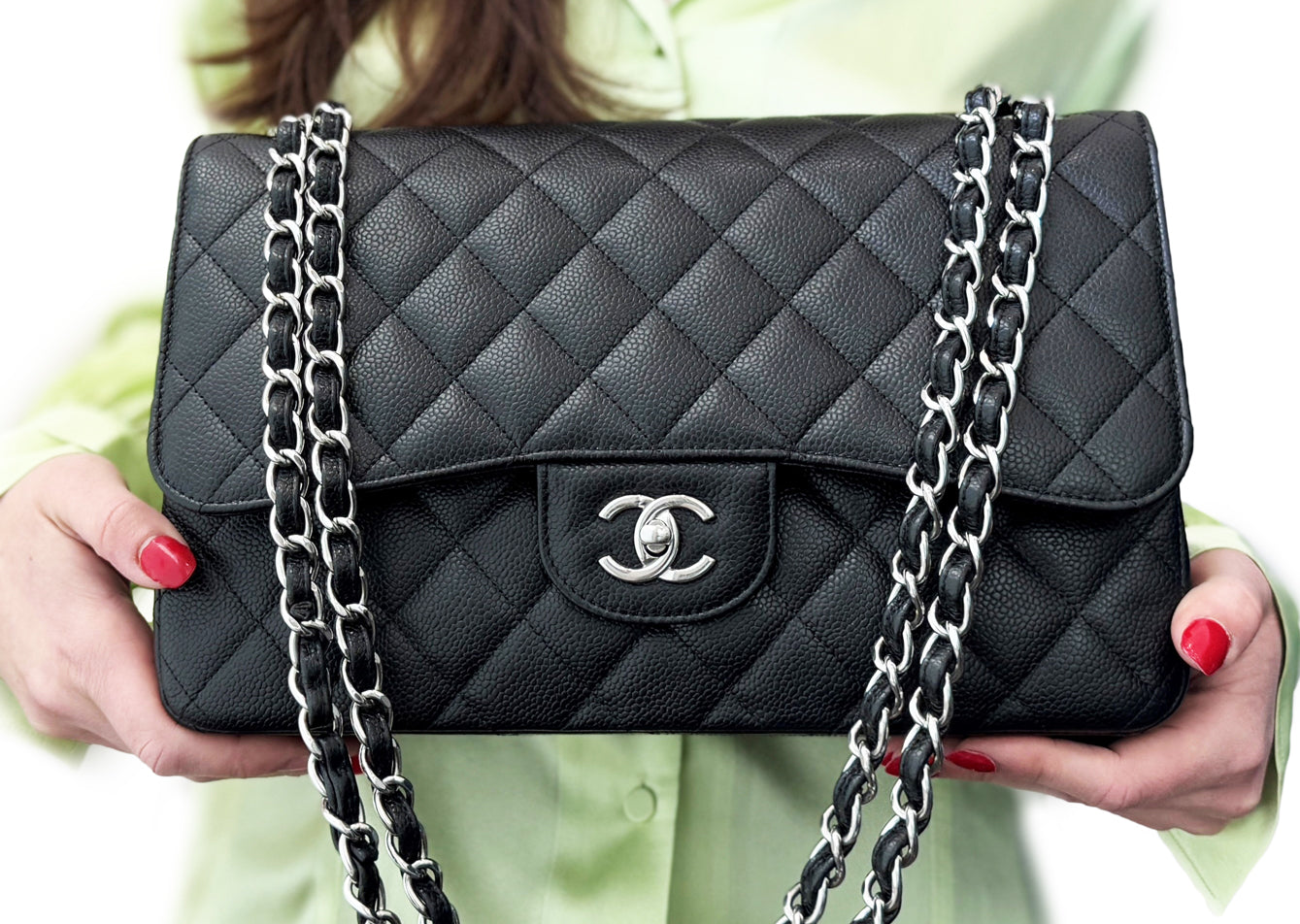 A woman in a green top  holding a black Chanel flap handbag.