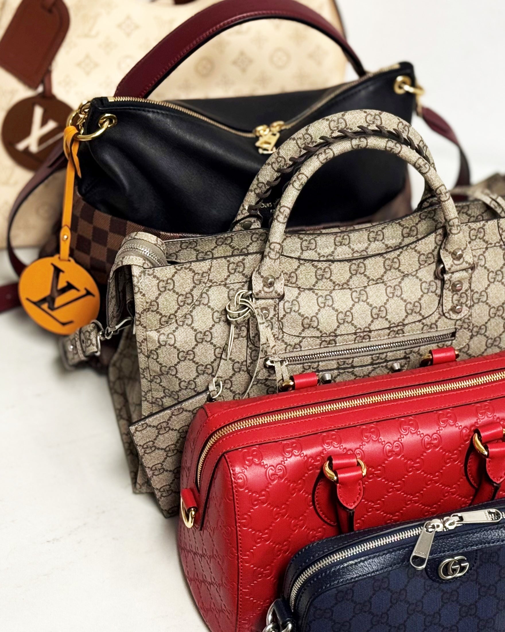 An assortment of luxury handbags from Gucci and Louis Vuitton.