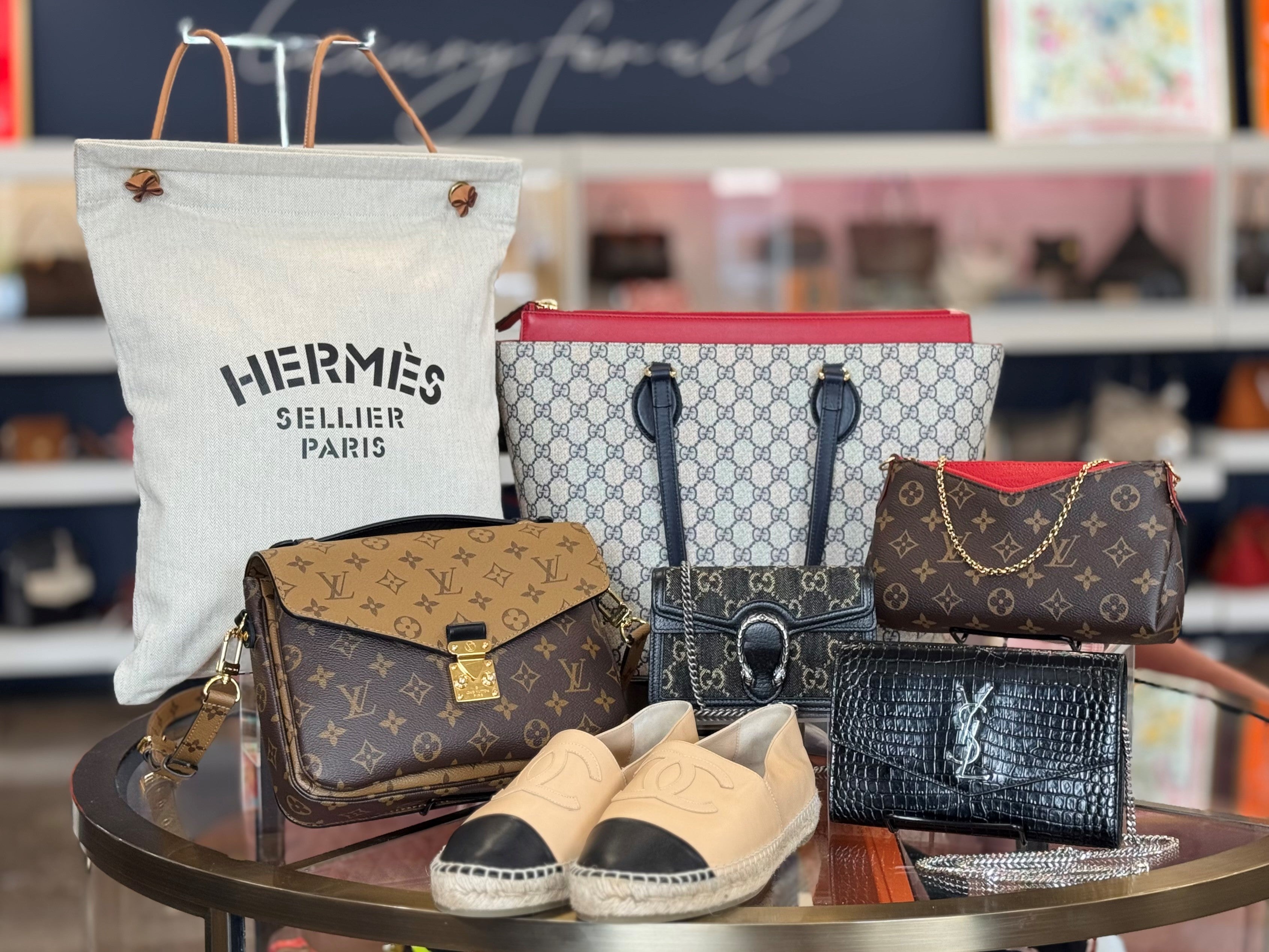 Collection of designer handbags and shoes on a table with blurred store background