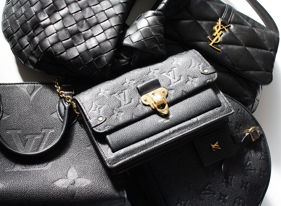 A collection of black leather designer handbags on a white background.