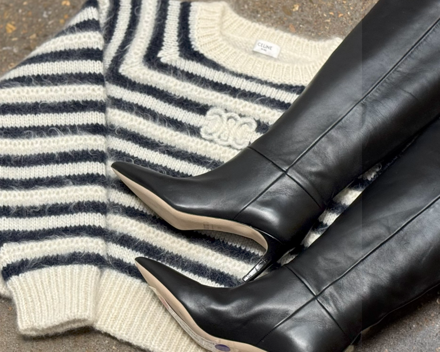 Black knee-high boots on a striped sweater with visible brand label.