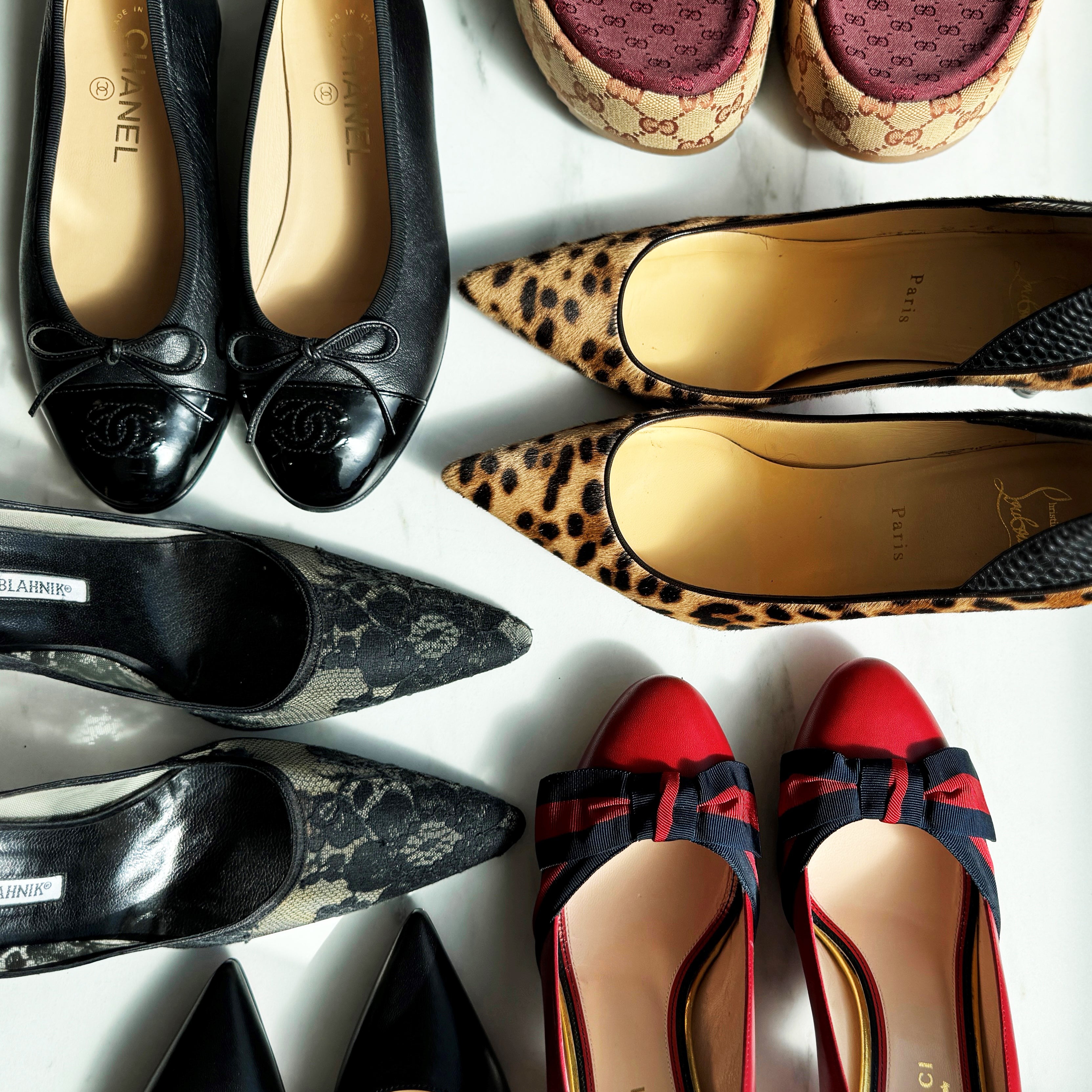A photo of a variety of luxury designer shoes on a white marble background
