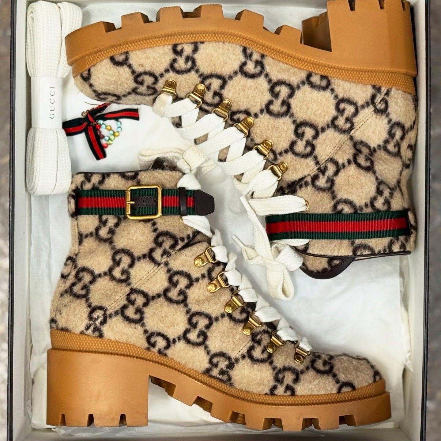 Beige Gucci boots with brown soles and white laces in a box.