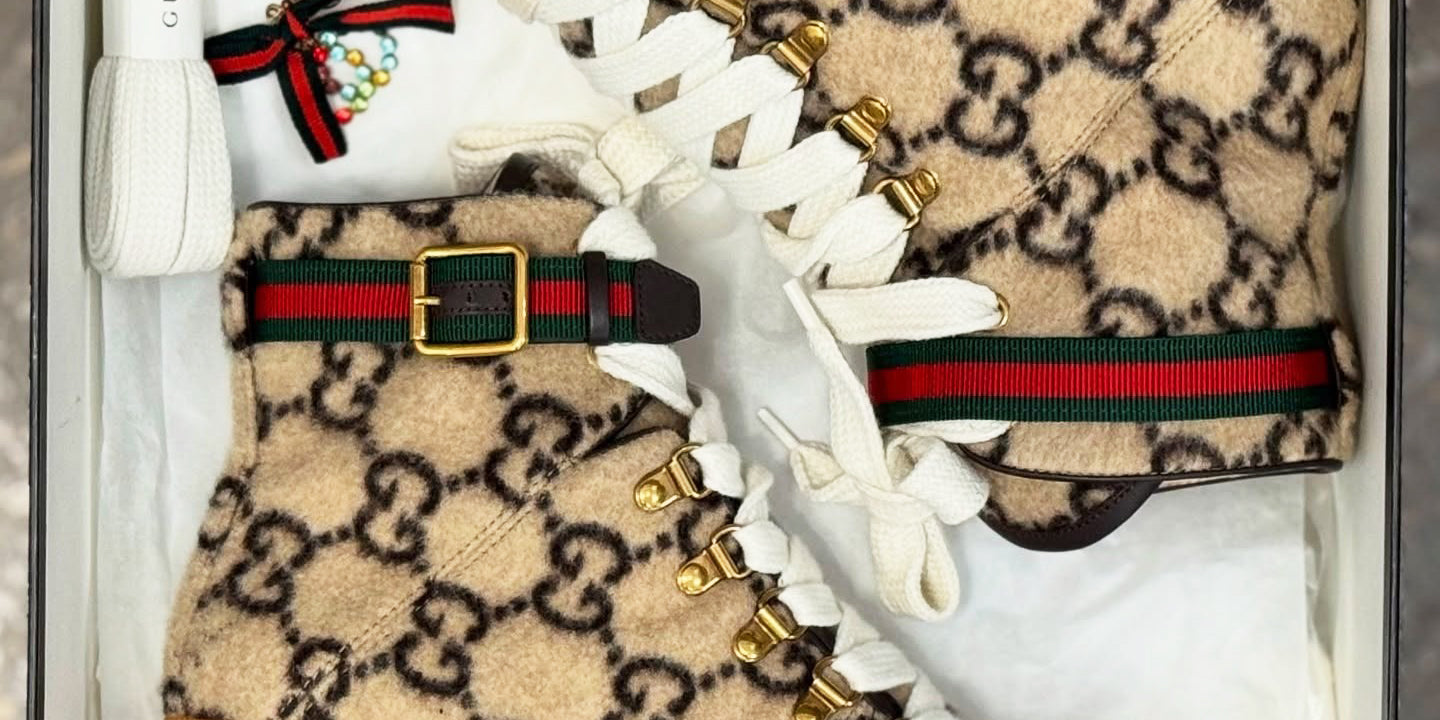 Beige Gucci boots with brown soles and white laces in a box.