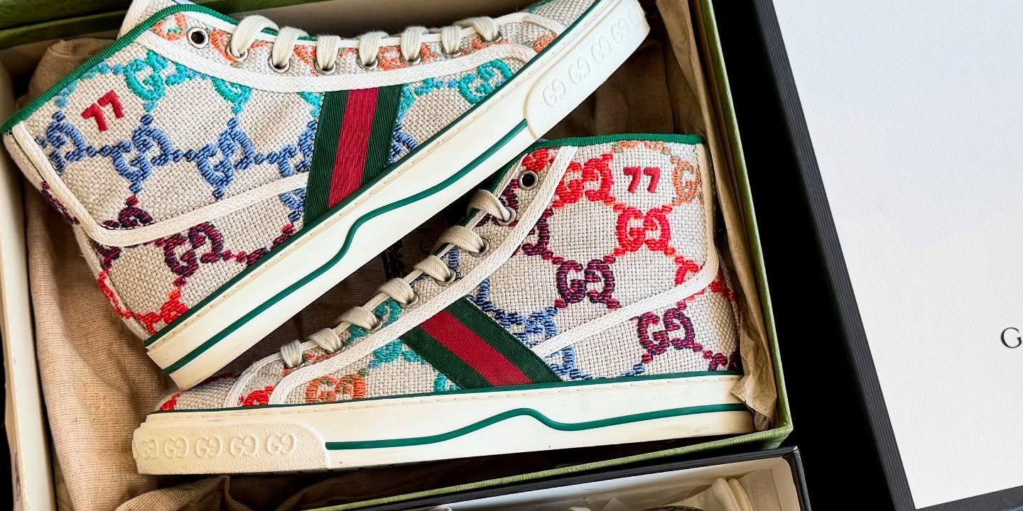 Colorful Gucci sneakers in open boxes with a Gucci box in the background.