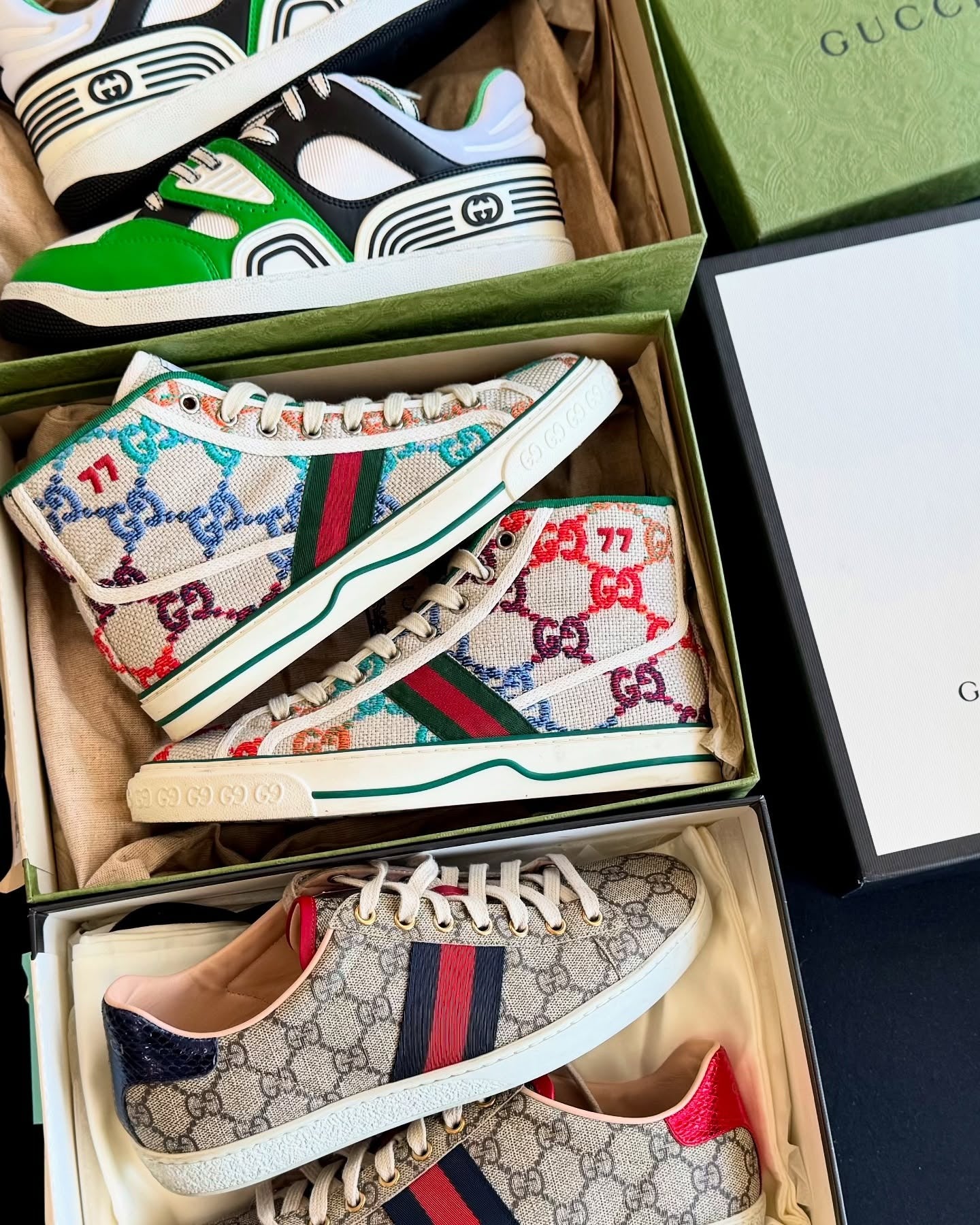 Colorful Gucci sneakers in open boxes with a Gucci box in the background.