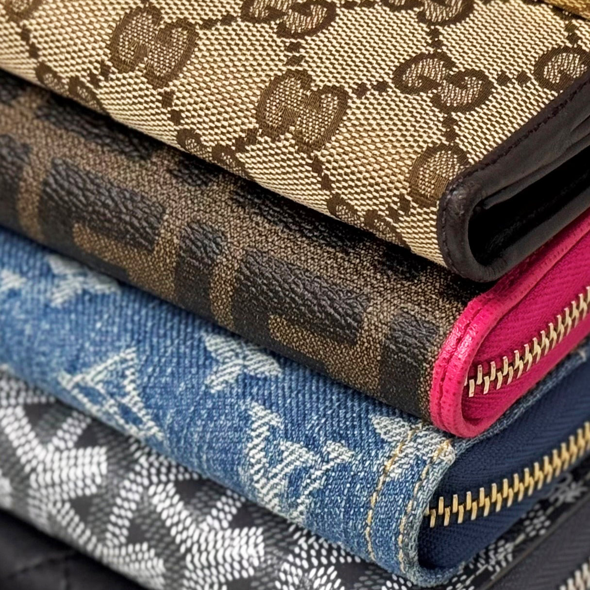 A stack of patterned wallets from Gucci, Fendi, Louis Vuitton, Goyard, and Chanel.